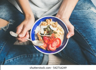 Eating healthy breakfast bowl. Yogurt, granola, seeds, fresh and dry fruits and honey in blue ceramic bowl in woman' s hands. Clean eating, dieting, detox, vegetarian food concept - Shutterstock ID 542716249