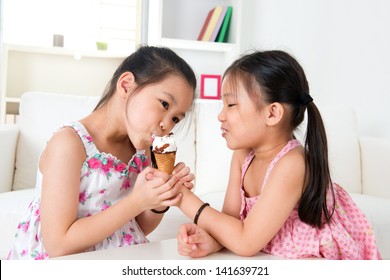 Eating Ice Cream. Asian Girls Sharing An Ice Cream. Beautiful Children Model At Home.