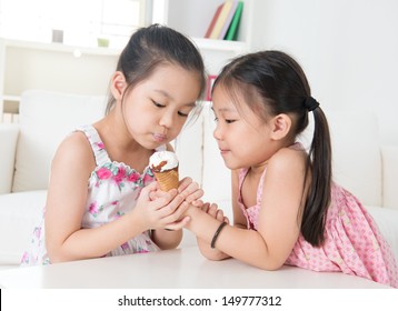 Eating Ice Cream Cone. Asian Children Sharing An Ice Cream. Beautiful Girls Model At Home.