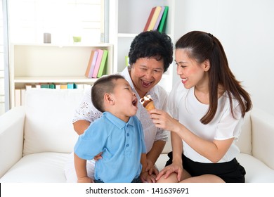 Eating Ice Cream. Happy Asian Family At Home, Grandparent, Parent And Grandchild Sharing An Ice Cream. Home Indoor With Decoration.