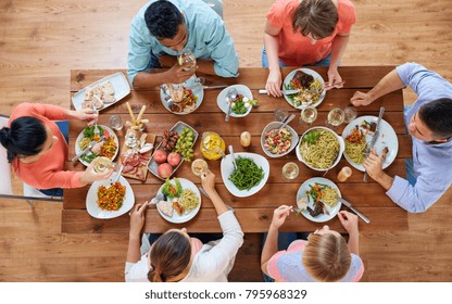 eating and leisure concept - group of people having dinner at table with food