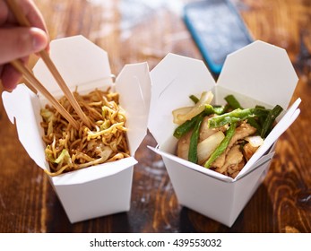 eating lo mein out of chinese take out box wih chopsticks