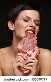 Eating Meat. Hungry Woman With Red Lips Ripping Raw Meat With Teeth. Portrait Of Healthy Girl With Beautiful Face Makeup Biting Beef Steak Meat With Greed. Food And Nutrition Concept. High Resolution