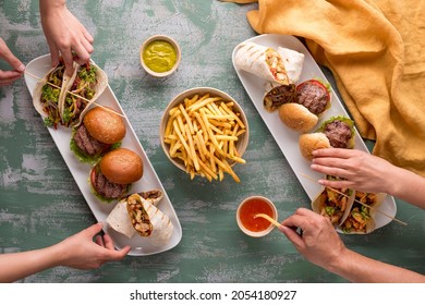 Eating Mini Burger,taco And Chicken Wrap With Friends.hands Reaching For Food