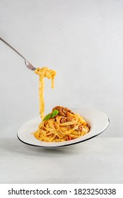 Eating pasta. Egg pasta tagliatelle with bolognese sauce made from meat and tomato sauce. Traditional italian dish from Bologna. Dynamic photo. Minimalism. Light grey background. Copy space. - Shutterstock ID 1823250338