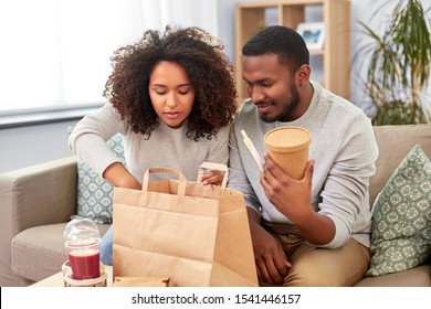 Eating And People Concept - Happy African American Couple With Takeaway Food And Drinks At Home