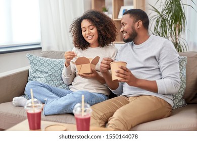 Eating And People Concept - Happy African American Couple With Takeaway Food And Drinks At Home