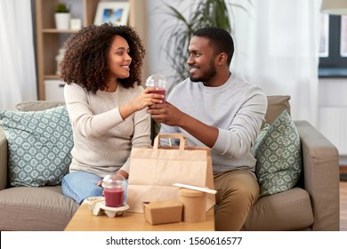 Eating And People Concept - Happy African American Couple With Takeaway Food And Drinks At Home