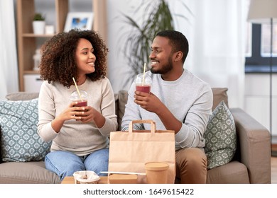 Eating And People Concept - Happy African American Couple With Takeaway Food And Drinks At Home