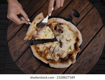 Eating pizza at the restaurant. Top view of female hands serving a slice of pizza with mozzarella cheese, mushrooms, bacon, sliced chives and garlic. - Powered by Shutterstock