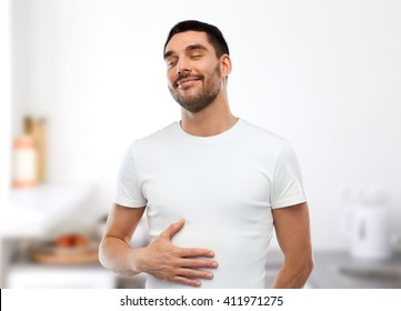 Eating, Satisfaction And People Concept - Happy Full Man Touching His Tummy Over Kitchen Background