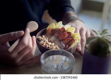 Eating A Smoothie Acai Bowl Decorated With Strawberries, Apple And Crushed Almonds