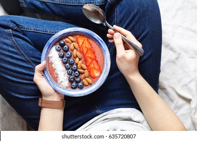 Eating smoothies breakfast bowl. Yogurt, strawberry, blueberry, seeds, coconut, fresh and dry fruits in blue ceramic bowl in woman' s hands. Clean eating, dieting, detox, vegetarian food concept - Powered by Shutterstock