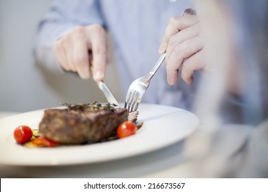 eating stake from plate with fork and knife man hands