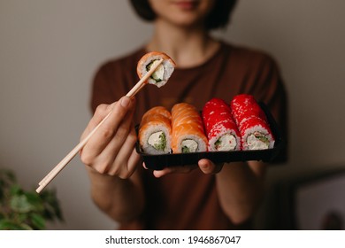 Eating sushi with chopsticks close up, food takeout and delivery service, salmon sushi rolls, tasty meal, sushi delivery
