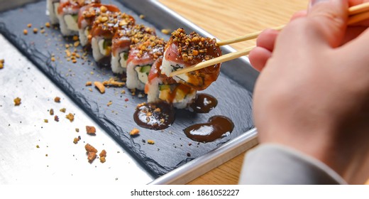 Eating sushi, still life, eating out concept. Young man in restaurant or at home eats Japanese sushi rolls set. Close up on sushi.