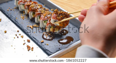 Eating sushi, still life, eating out concept. Young man in restaurant or at home eats Japanese sushi rolls set. Close up on sushi.