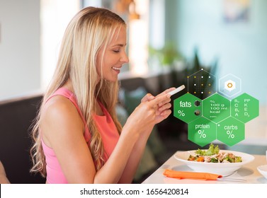 Eating, Technology And People Concept - Happy Woman With Smartphone And Salad For Lunch At Restaurant Over Food Nutritional Value Chart