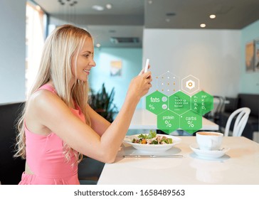 Eating, Technology And People Concept - Happy Woman With Smartphone And Salad For Lunch At Restaurant Over Food Nutritional Value Chart