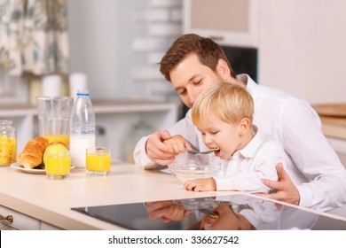 Eating It Up. Father Carefully Feeds His Small Kid With Milk Cereal.