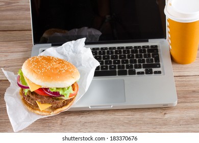 Eating At Work Place Fast Food Near Laptop On Wooden Table 