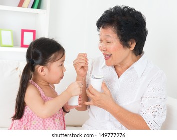 Eating Yogurt. Happy Asian Family Eating Yoghurt At Home. Beautiful Grandmother And Grandchild, Healthcare Concept.