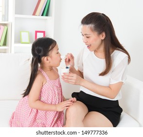 Eating Yogurt. Happy Asian Family Eating Yoghurt At Home. Beautiful Mother  Feeding Child, Healthcare Concept.