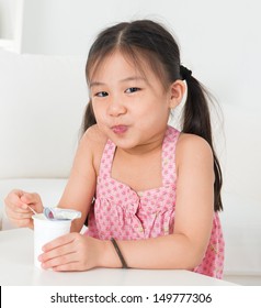 Eating yogurt. Happy Asian kid eating yoghurt at home. Beautiful child. Healthcare concept.