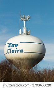 Eau Claire, WI / USA - March 23 2019: Eau Claire Water Tower And Antennae On Horizon Above Treeline With Blue Sky And Clouds In Background