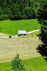 Eben Im Pongau, Salzburg - Austria - 06-16-2021: A Small Chapel Sits Amidst Green Meadows And Dense Forests In The Austrian Alps