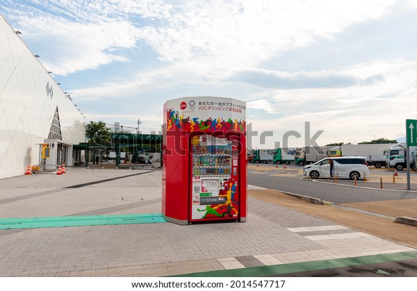 Ebina Service\
Area, Kanagawa Prefecture, Japan - July 10, 2021: Coca Cola drink\
vending machine with Tokyo 2020 Olympic Games design. Blue sky and\
clouds background. Front\
view.