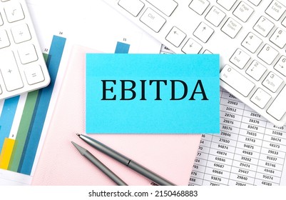 EBITDA text on a blue sticker on chart with calculator and keyboard,Business concept