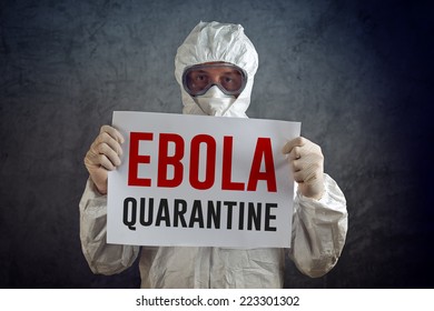 Ebola Quarantine Sign Held By Medical Health Care Worker Wearing Protective Gown, Gloves, Mask And Goggles.