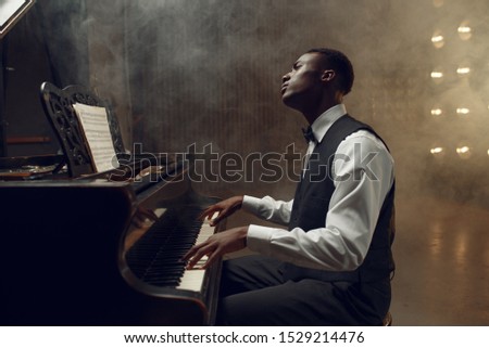 Ebony grand piano player playing on the stage