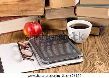 E-book and coffee in front of  stack of books. Concept of reading and cognition. Selective focus.