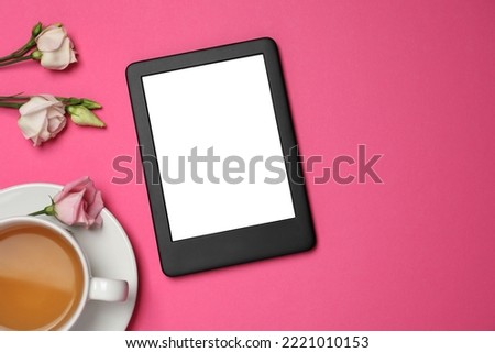 E-book reader with cup of tea and flowers on pink background, flat lay. Space for text