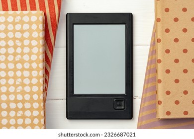 E-book reader device on background of paper books