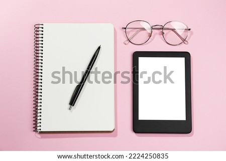 E-book reader, notebook and glasses on pink background, flat lay. Space for text