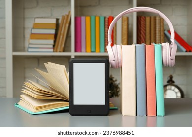 E-book reader on table against book shelves