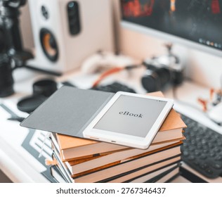 Ebook reader placed on stack of books in modern workspace. Digital device contrasts with printed literature, representing blend of technology and traditional reading in creative and productive 