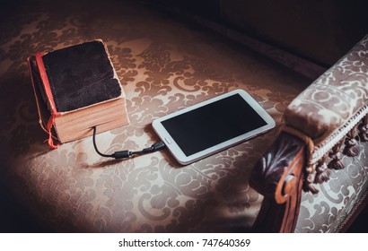 Ebook Or Tablet Pc, Ebook Reader And Old Book Connected With Cable. Tablet Download Information From Book. New Technology Concept. Concept Of Technology Progress. Old Vs New.Vintage Furniture.