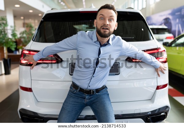 eccentric cheerful man fooling\
around in a car dealership not wanting to give away his new bought\
car