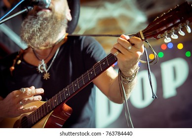  eccentric man in a hat performs at a music bar. Sings songs and plays Irish bouzouki (girar)
