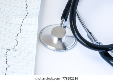 ECG Paper Tape Stethoscope On White Background Close-up Front View. Diagnosis And Treatment Of Diseases Of The Heart Electrical Conduction System And Rhythm Disturbances Such As Arrhythmia, Blockade