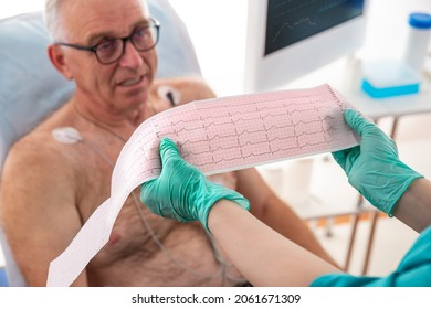 ECG Showing A Bundle Branch Block. Cardiologist Examining Senior Patient With Holter Device In The Department Of Cardiology In The Hospital. Matury Man On Clinic Couch