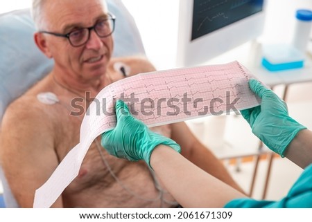 ECG showing a bundle branch block. Cardiologist examining senior patient with Holter device in the department of cardiology in the hospital. Matury man on clinic couch
