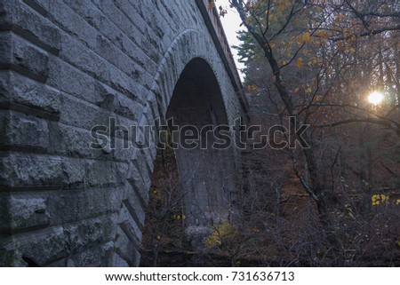 Echo Bridge over the Charles River in the Hemlock Gorge Reservation, Newton, MA with the late afternoon sun reflecting through fall trees