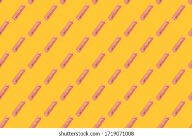 Eclair seamless pattern on a yellow background. Eclair with berry pink glaze and sweet sprinkles is patterned on yellow.