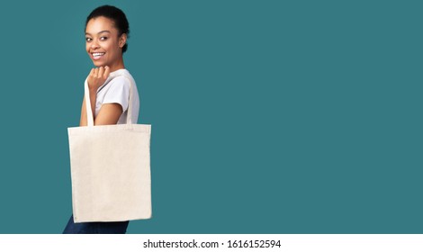 Eco Bag. Afro Woman Holding White Blank Canvas Tote Handbag Shopper Standing Over Turquoise Studio Background. Panorama, Free Space