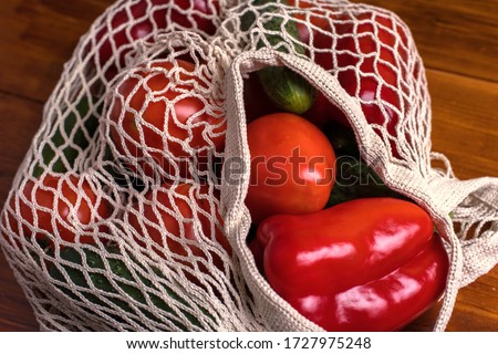 Eco bag string bag with vegetables cucumbers and tomatoes on a wooden background. Zero West Flat Lay, Top view